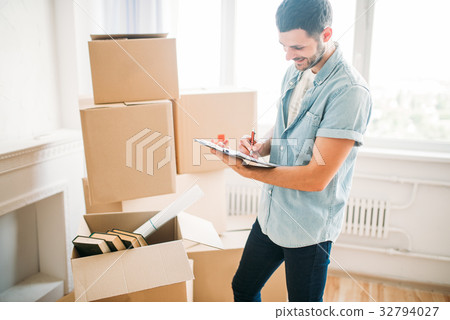Man with notebook among boxes, housewarming Man with notebook among boxes, housewarming 32794027
