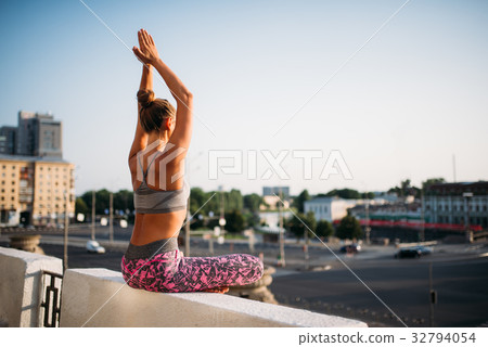 Young woman in yoga pose, city on background 32794054