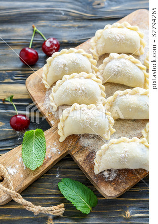 Dumplings with cherries on floured board. Dumplings with cherries on floured board. 32794265