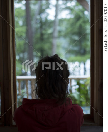 Young brown haired female looking out house window Young brown haired female looking out house window 32797010