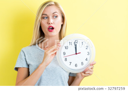 Woman holding clock showing nearly 12 Woman holding clock showing nearly 12 32797259