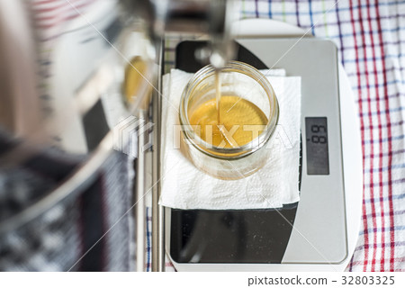 Beekeeper filling up the fresh golden new honey Beekeeper filling up the fresh golden new honey 32803325
