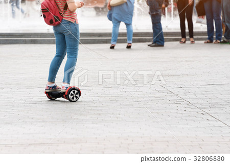 Young woman riding a hoverboard on the city square 32806880