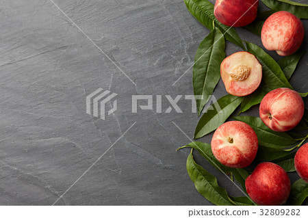 Fresh peaches fruits with leaves on stone background Fresh peaches fruits with leaves on stone background 32809282