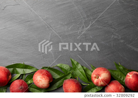 Fresh peaches fruits with leaves on stone background Fresh peaches fruits with leaves on stone background 32809292