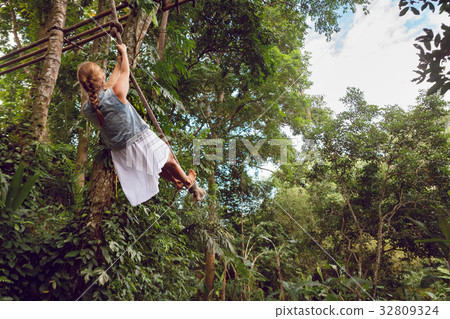 Woman on rope swing on wild jungle background 32809324