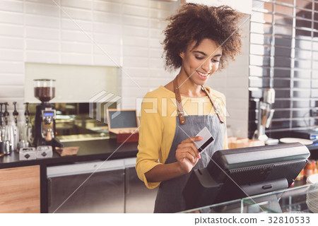 Cheerful young woman cashier is working in cafe Cheerful young woman cashier is working in cafe 32810533