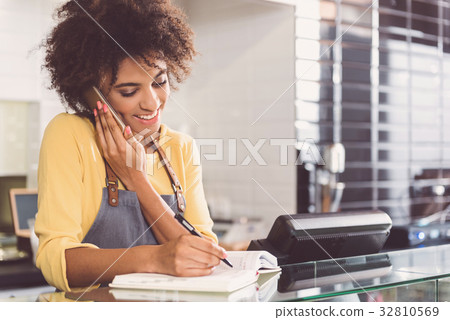 Cheerful mulatto waitress is talking on smartphone 32810569