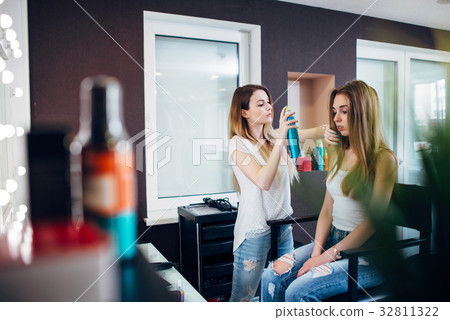 Hairdresser using hairspray on girl s hair 32811322