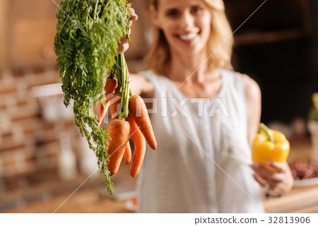 Bright cheerful lady picking up some carrots 32813906