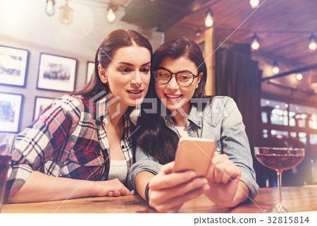 Cute happy females looking at phone Cute happy females looking at phone 32815814