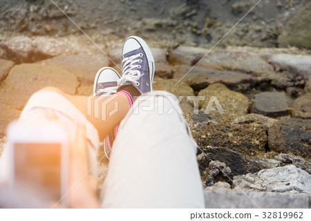 Blue sneaker on girl leg over green sea background 32819962