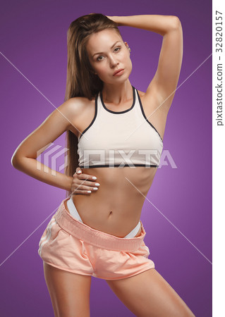 Muscular young woman athlete posing at studio 32820157
