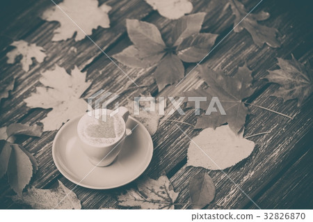 Autumn maple leaves and coffee cup on table. Autumn maple leaves and coffee cup on table. 32826870