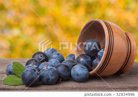 blackthorn berries in a wooden bowl on  table wit 32834996
