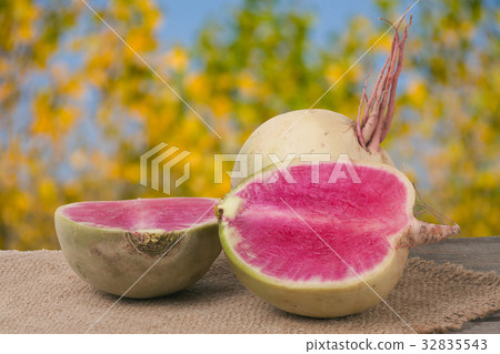 One whole and sliced watermelon radish on a wooden 32835543