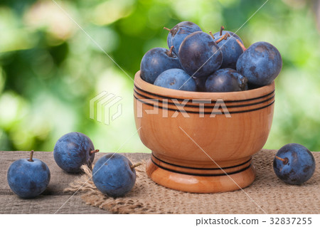 blackthorn berries in a wooden bowl on table with 32837255