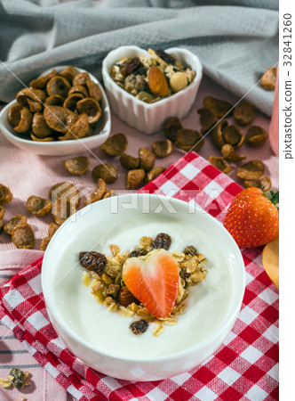 Breakfast set. Strawberry fruit over the yogurt in white bowl with Oat granola and nuts on table set background, serve with pink milk in Bottle, top view, Healthy food concept Breakfast set. Strawberry fruit over the yogurt in white bowl with Oat granola and nuts on table set background, serve with pink milk in Bottle, top view, Healthy food concept 32841260