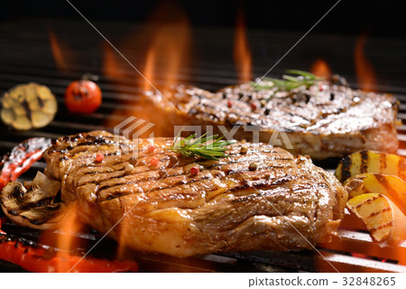 图库照片: grilled pork steak on the flaming grill