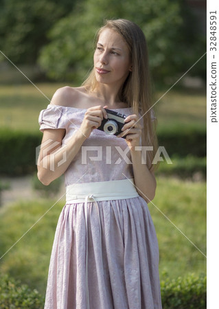 Beautiful woman is holding old fashioned camera in 32848591