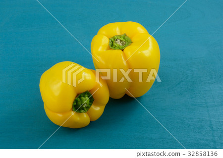 Two raw whole yellow bell peppers on blue wood 32858136