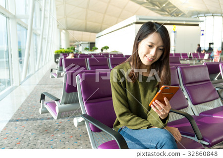 Woman on smart phone at gate waiting in terminal 32860848