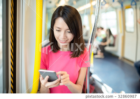 Young woman looking at cellphone inside train compartment Young woman looking at cellphone inside train compartment 32860987