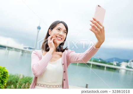 Woman taking selfie by mobile phone in Macao city Woman taking selfie by mobile phone in Macao city 32861018