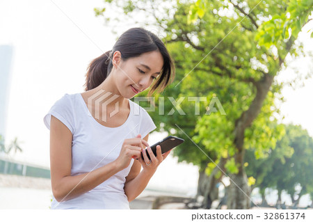 Woman using mobile phone in the park Woman using mobile phone in the park 32861374