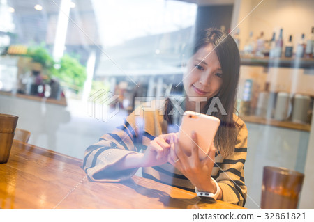 Woman using cellphone at coffee shop Woman using cellphone at coffee shop 32861821