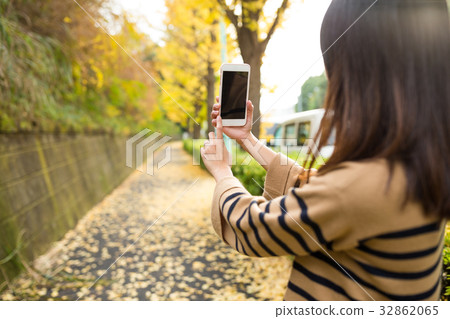 Woman taking photo by cellphone at autumn season Woman taking photo by cellphone at autumn season 32862065