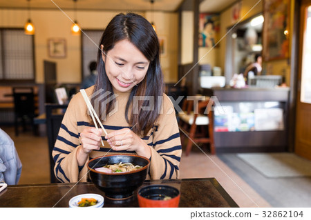 Woman enjoy japanese ramen in restaurant Woman enjoy japanese ramen in restaurant 32862104