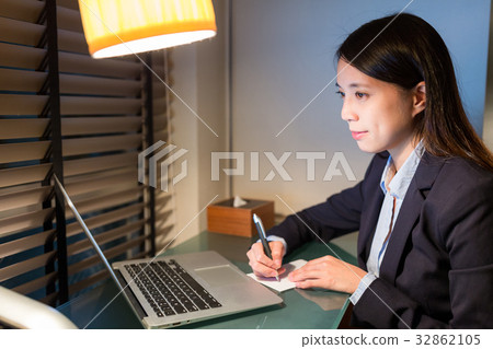 Businesswoman writing on the note with laptop computer Businesswoman writing on the note with laptop computer 32862105