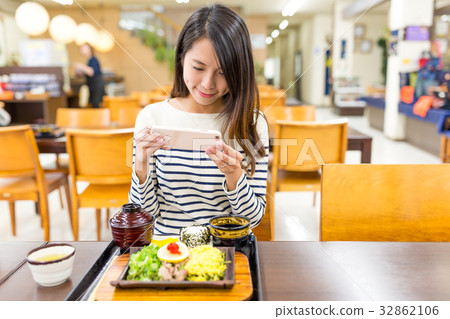 Woman taking photo on japanese cuisine in restaurant Woman taking photo on japanese cuisine in restaurant 32862106