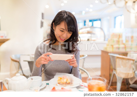 Woman taking photo on her slice of cake Woman taking photo on her slice of cake 32862157