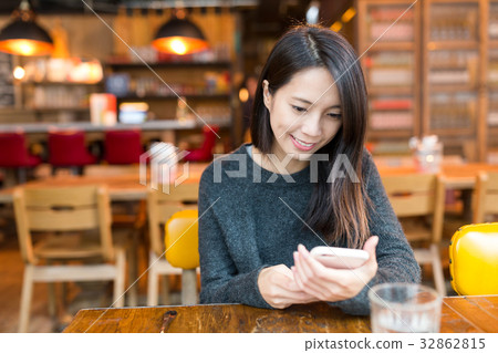 Woman using mobile phone in restaurant Woman using mobile phone in restaurant 32862815