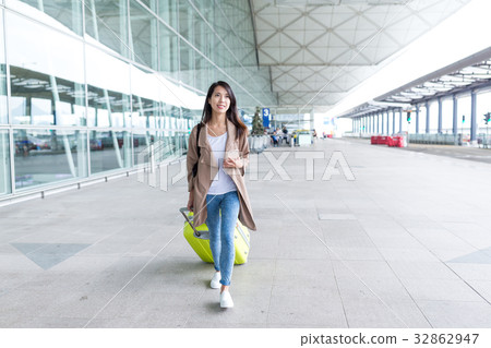 Woman walking with luggage in airport Woman walking with luggage in airport 32862947