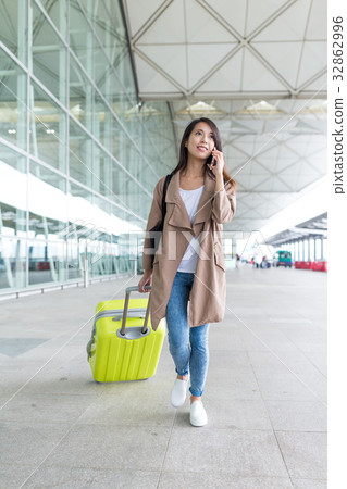 Young woman talk to cellphone and walking in airport Young woman talk to cellphone and walking in airport 32862996