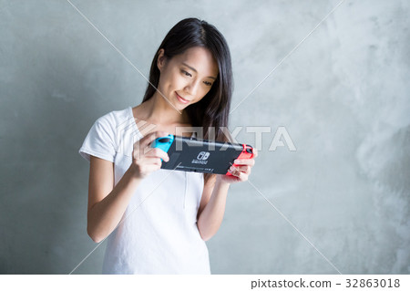 Hong Kong, 19 May 2017 -:Woman playing game on Nintendo Switch over gray background Hong Kong, 19 May 2017 -:Woman playing game on Nintendo Switch over gray background 32863018
