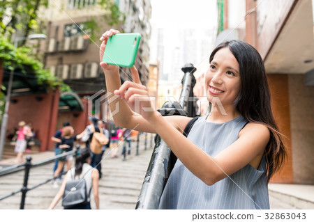 Woman taking photo with cellphone in Pottinger Street Woman taking photo with cellphone in Pottinger Street 32863043
