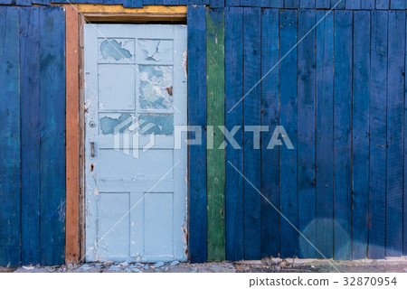 Old wooden light blue door in a dark blue wall Old wooden light blue door in a dark blue wall 32870954