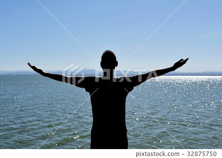 man with his arms in the air in front of the sea 32875750