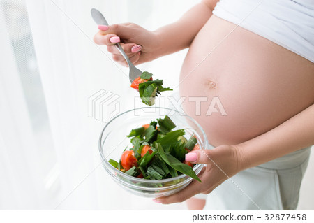 Pregnant woman starts to eat fresh salad Pregnant woman starts to eat fresh salad 32877458