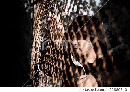 Depressed man sitting behind a fence steel mesh 32880740