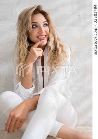 Sexy smiling blonde sitting on the floor in studio Sexy smiling blonde sitting on the floor in studio 32883494