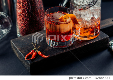 Red drink with ice. Cocktail making bar tools, strawberry and orange peel 32885845