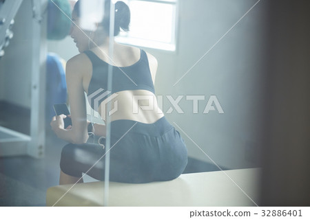 The woman is sitting, holding the phone and looking at something. 32886401