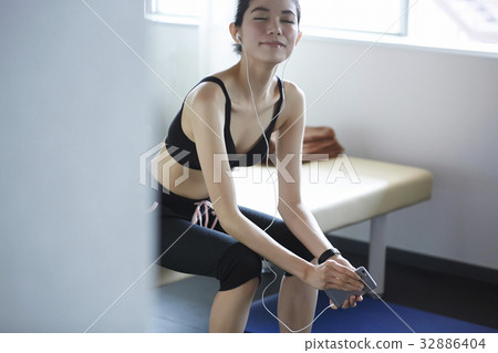 The woman is listening to music and relaxing in sport club The woman is listening to music and relaxing in sport club 32886404