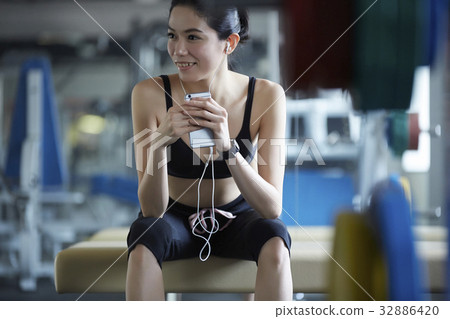 The woman with sportswear is sitting and smiling. The woman with sportswear is sitting and smiling. 32886420