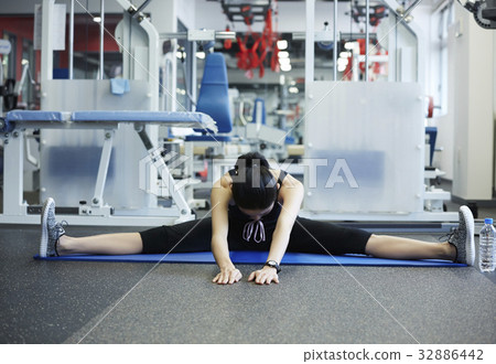 A trainee is stretching alone at a fitness club A trainee is stretching alone at a fitness club 32886442